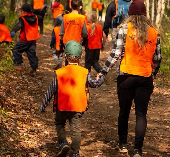 Photo of Children on a walk in the woods with child care professionals